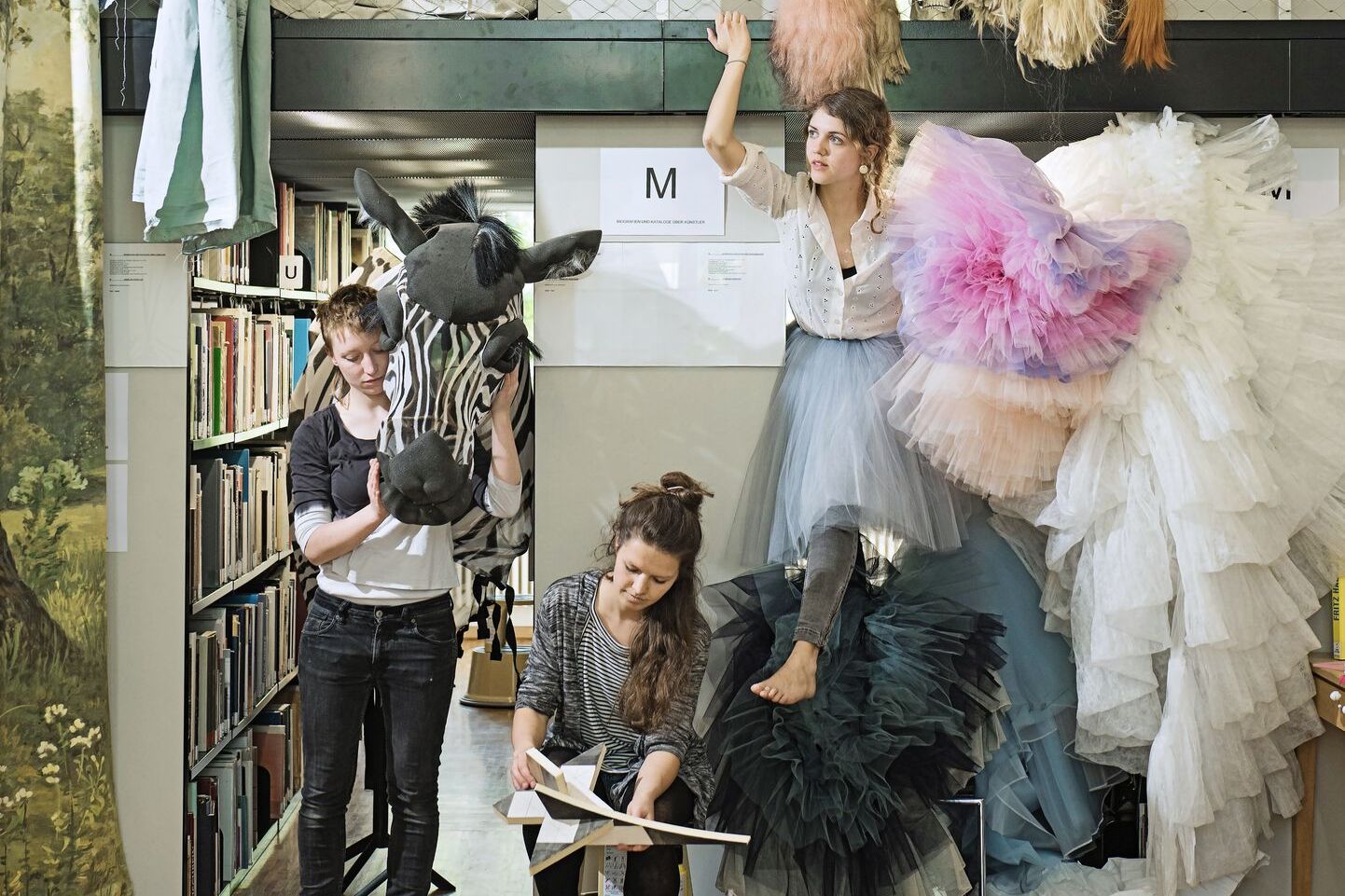 Fünf Studentinnen mit Kostümen in der Hochschulbibliothek.