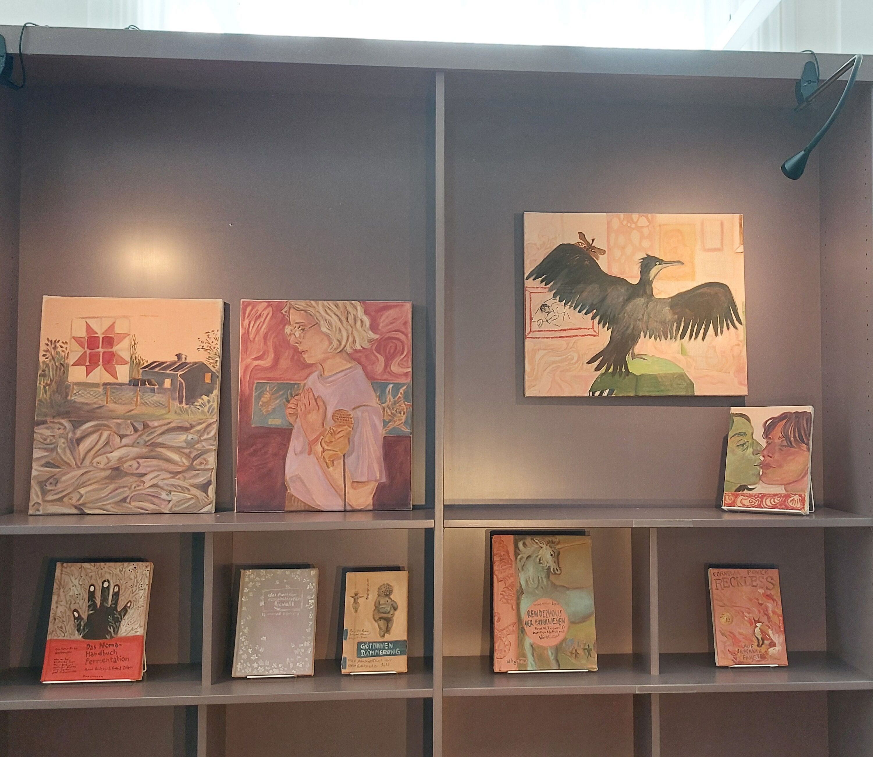 Regal mit Büchern und kleinformatigen Malereien on display