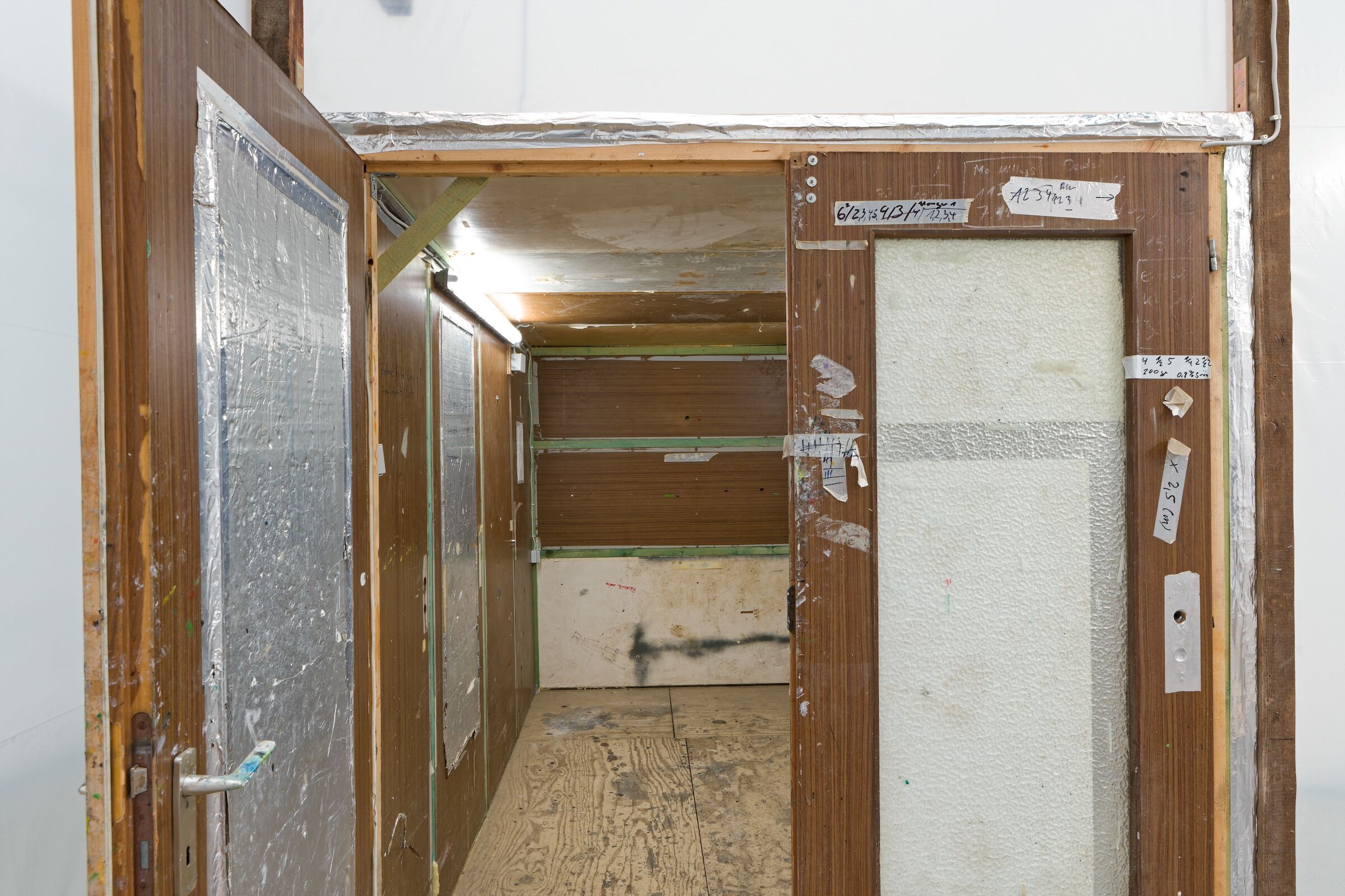 Raum im Raum, fotografiert durch offene Türen, die Nutzungsspuren zeigen.