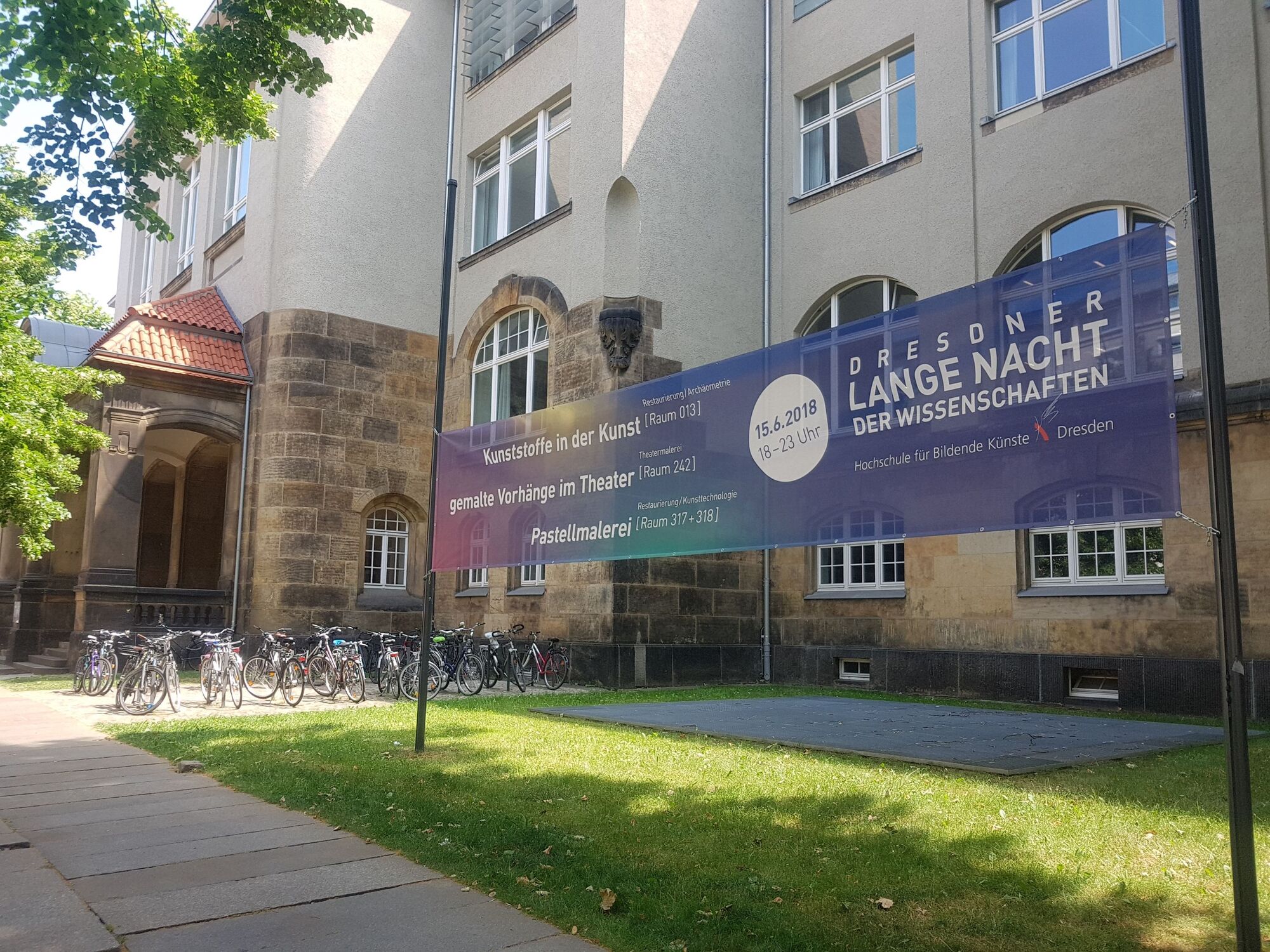 Der Gebäudekomplex der Hochschule an der Güntzstraße. Fahrräder vor der Eingang. Werbung für Lange Nacht der Wissenschaften im Vordergrund.
