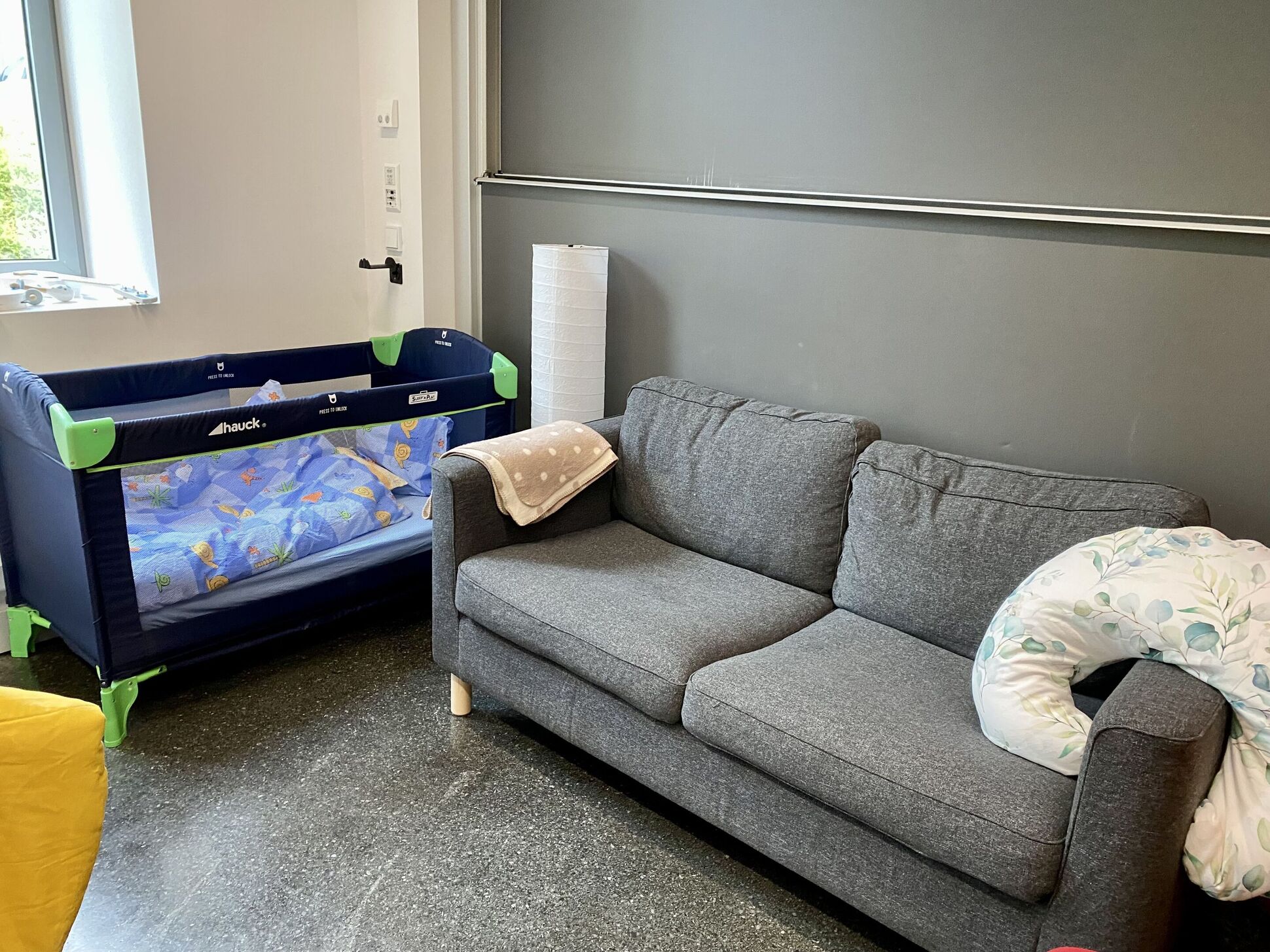 Eltern-Kind-Raum mit Babybett und Sofa