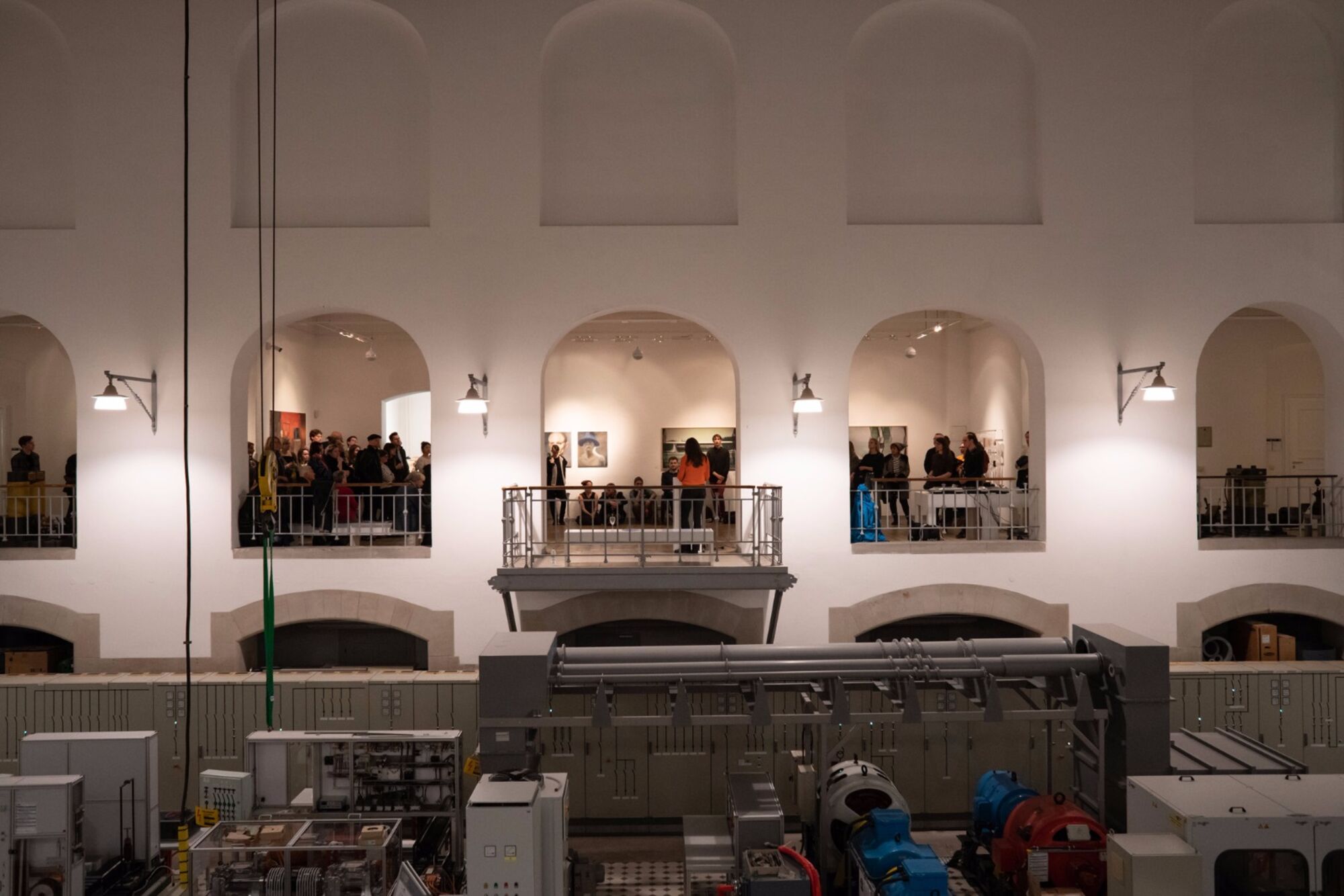 Ausstellungseröffnung der Künstlergruppe 2K17. Eine Frau hält eine Rede. Publikum hört zu.