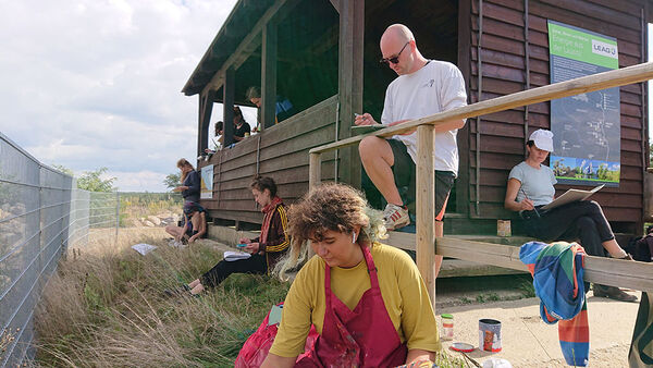 Foto mit Studierenden, Hintergrudn eine Holzhütte