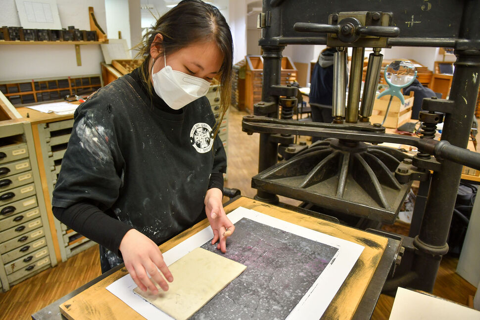 Workshop mit Jan Brokof - Holzschnitt und Blockdruck Foto Studentin an Druckpresse