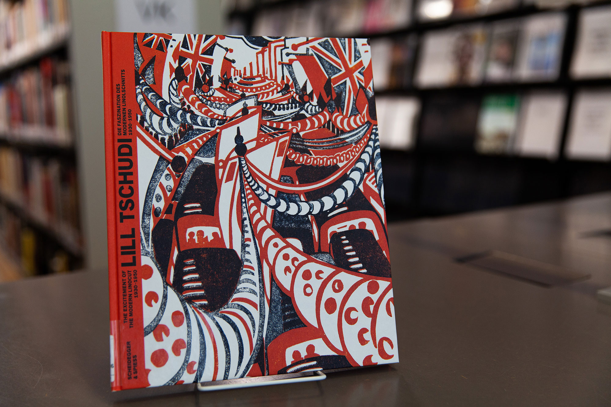 View of the book "Lill Tschudi: the fascination of the modern linocut", set up, library shelves in the background.