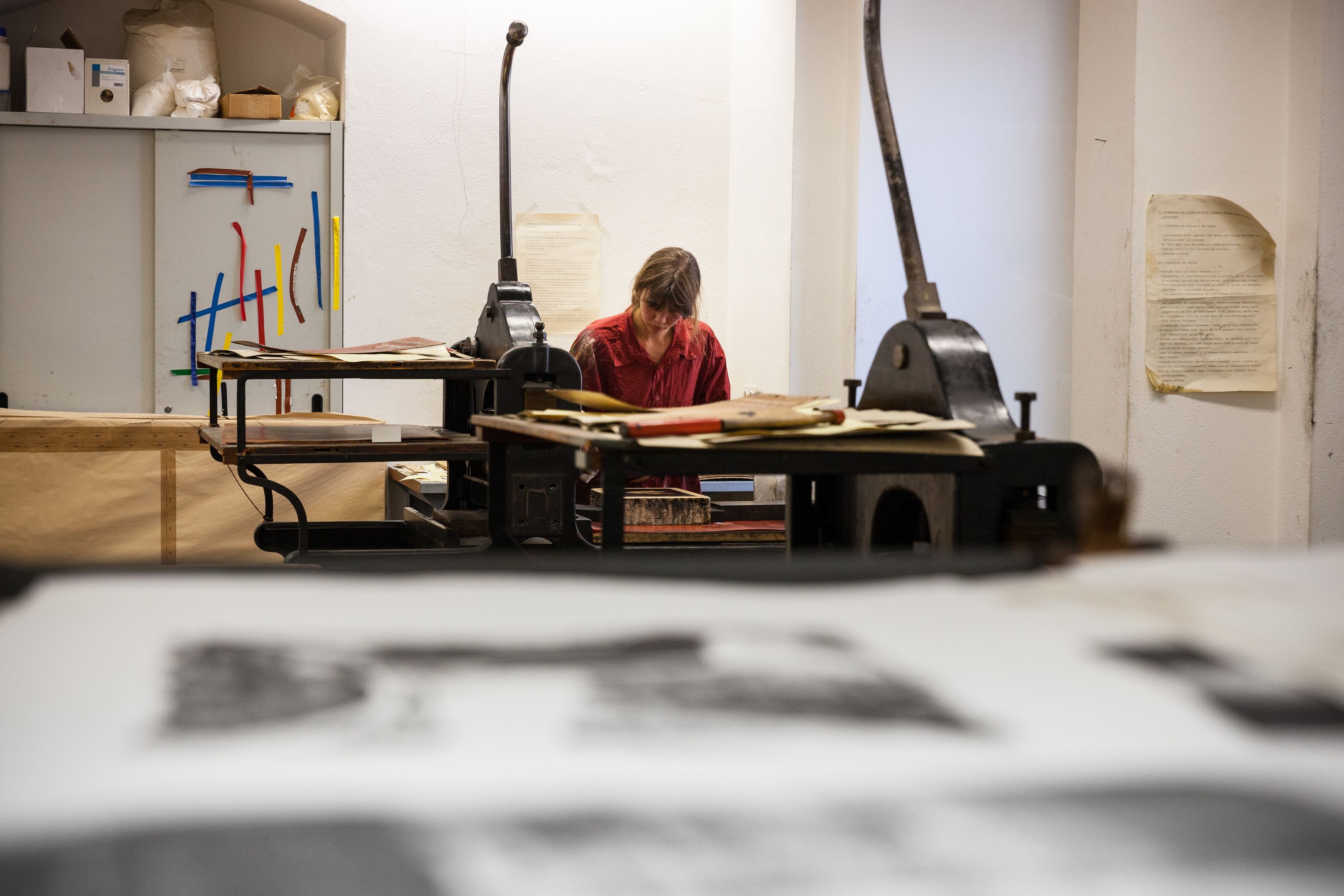 Werkstatt für Lithografie. Steinhandhebelpresse. Eine Studentin beim Arbeiten.