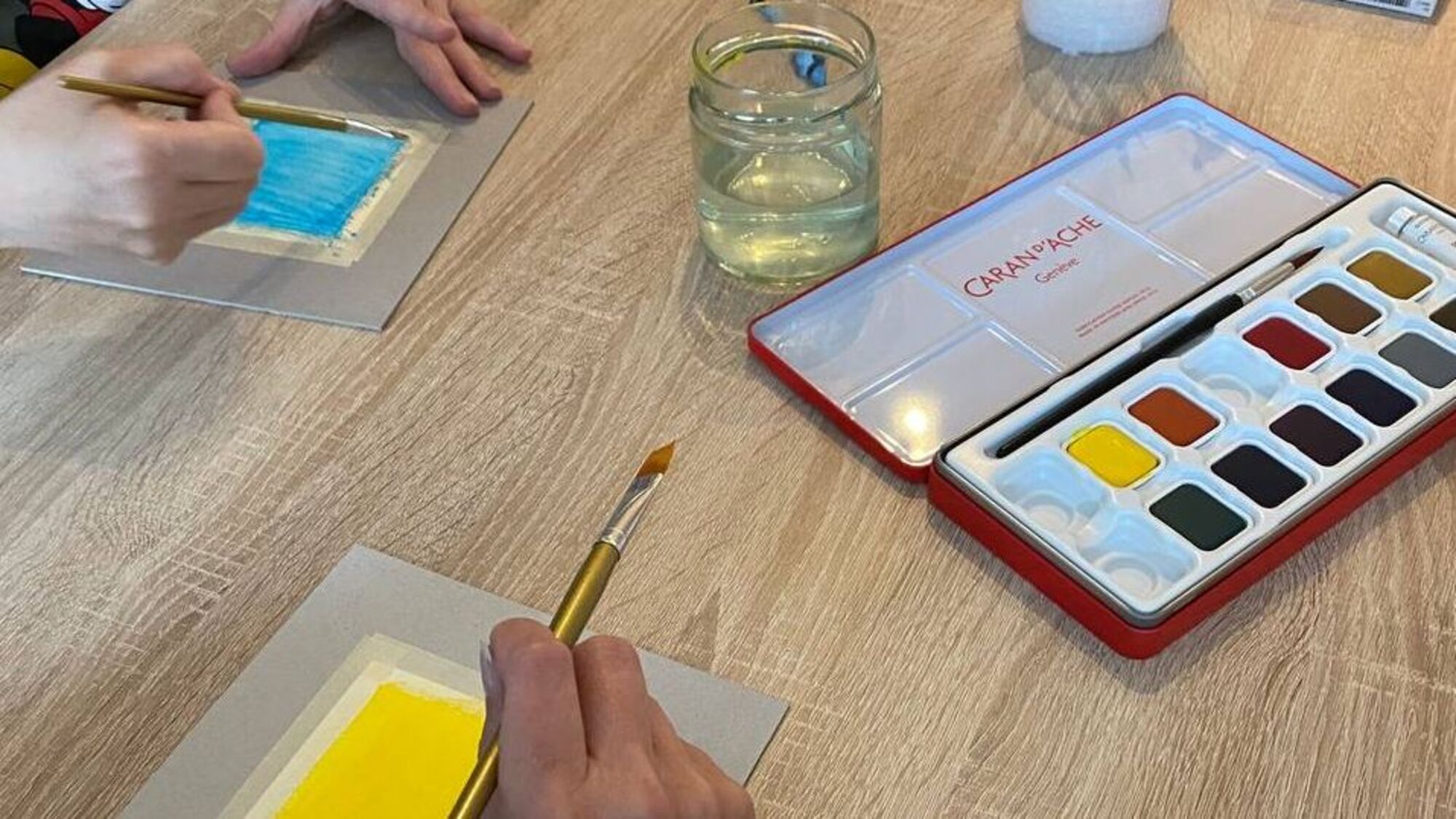 Nahaufnahme einer Malsituation mit Aquarellkasten und Pinseln