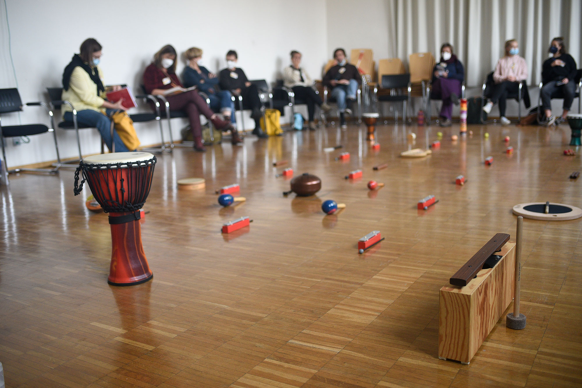 Workshopsituation bei der Tagung "Künstlerische Therapien und Spiritualität". Zu sehen ist ein Stuhlkreis in dessen Mitte Musikinstrumente liegen.