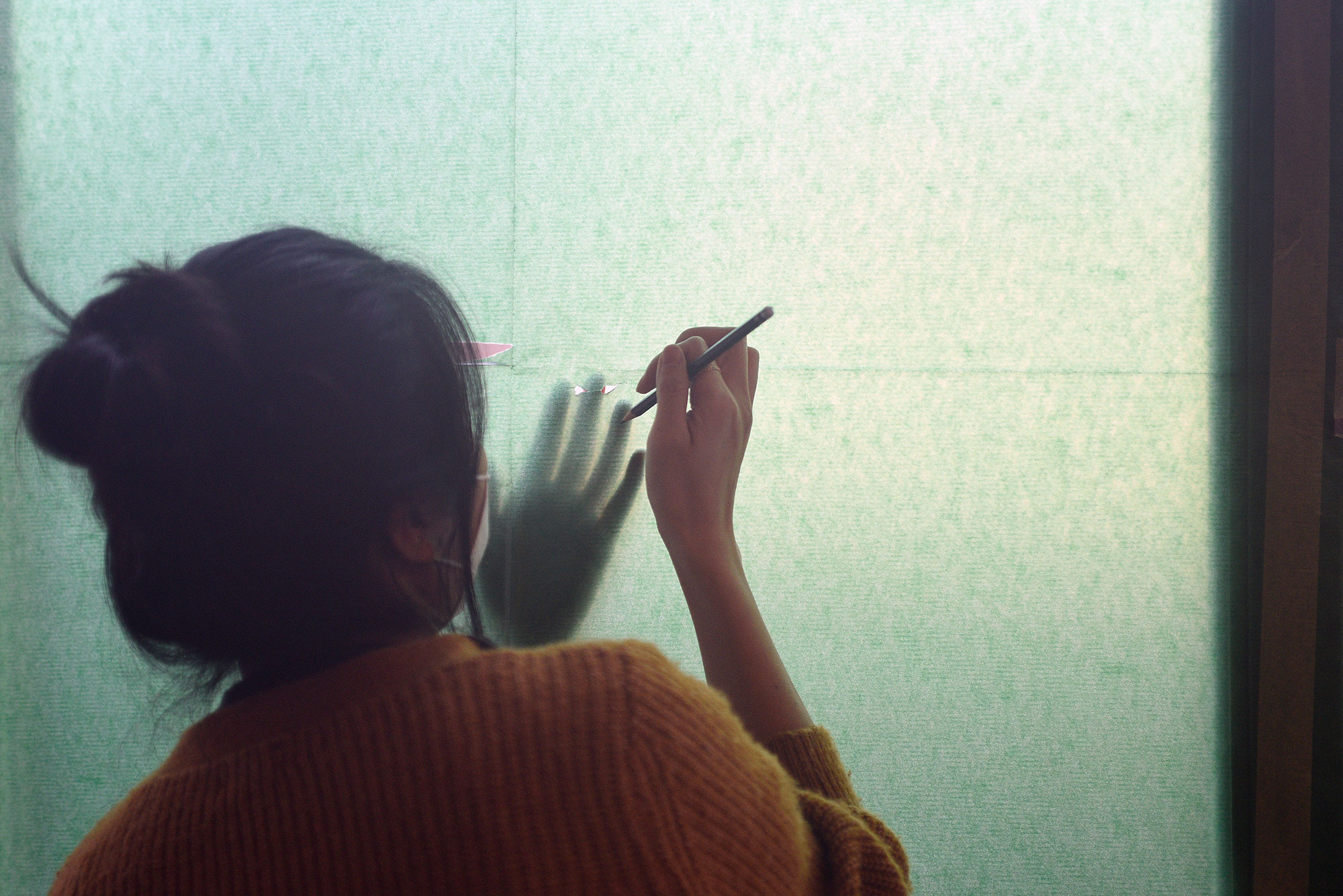 Eine Person malt auf eine Wand aus Transparentpapier.