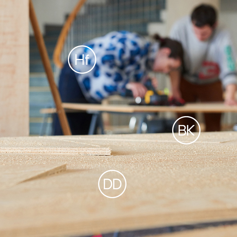Foto mit Holzschnitt und arbeitenden Studierende im Hintergrund