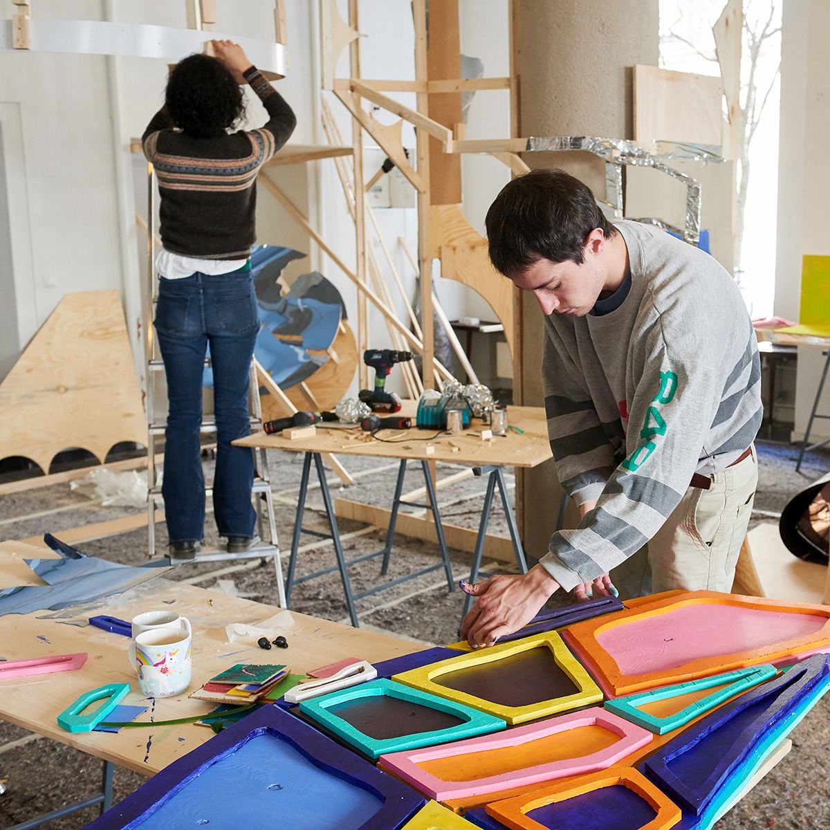 [Translate to Englisch:] Zwei Künstler:innen arbeiten dreidimensional mit bunten Materialien