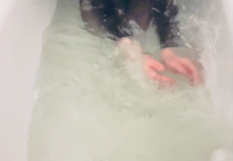 Hände wirbeln durch Wasser in einer Badewanne, die unterarme der Person sind zu sehen. Sie trägt ein schwarzes Oberteil.