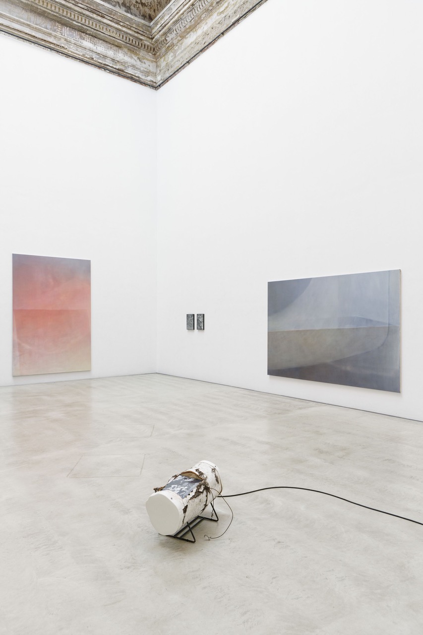 Ausstellungsansicht, großformatige Malereien in blau-grau und rosa mit kleiner Baumstamm Skulptur