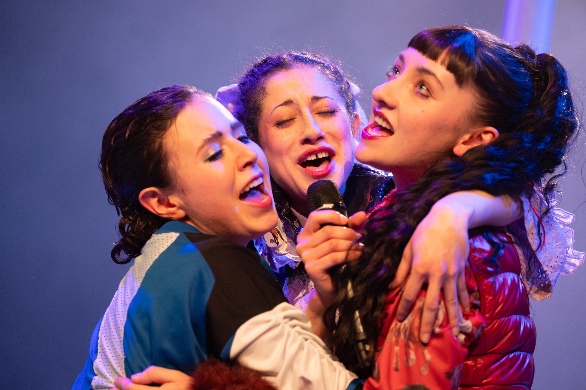 Drei Personen singen gemeinsam in ein Mikrofon