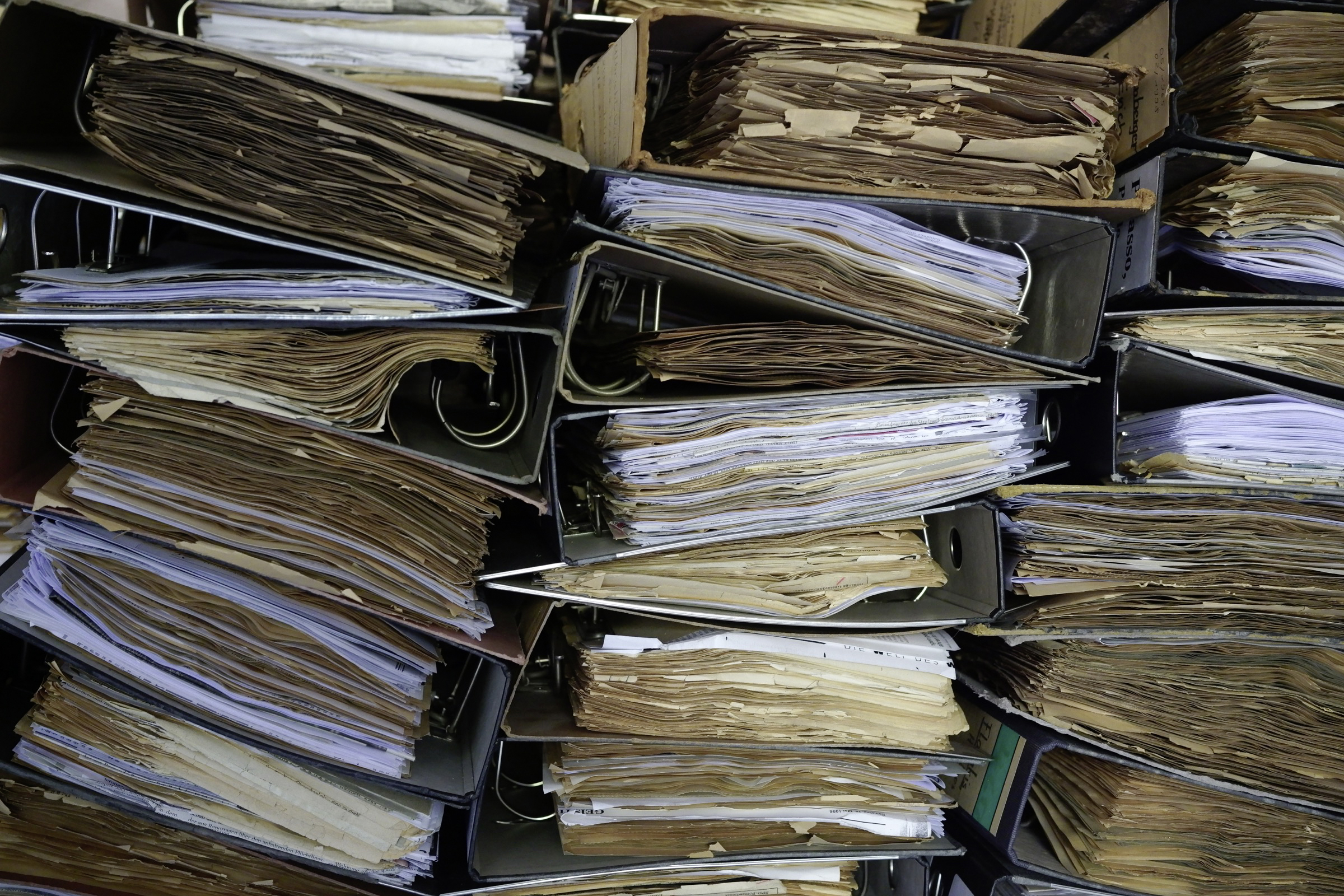 viele gestapelte Aktenordner mit gelblichen Papieren