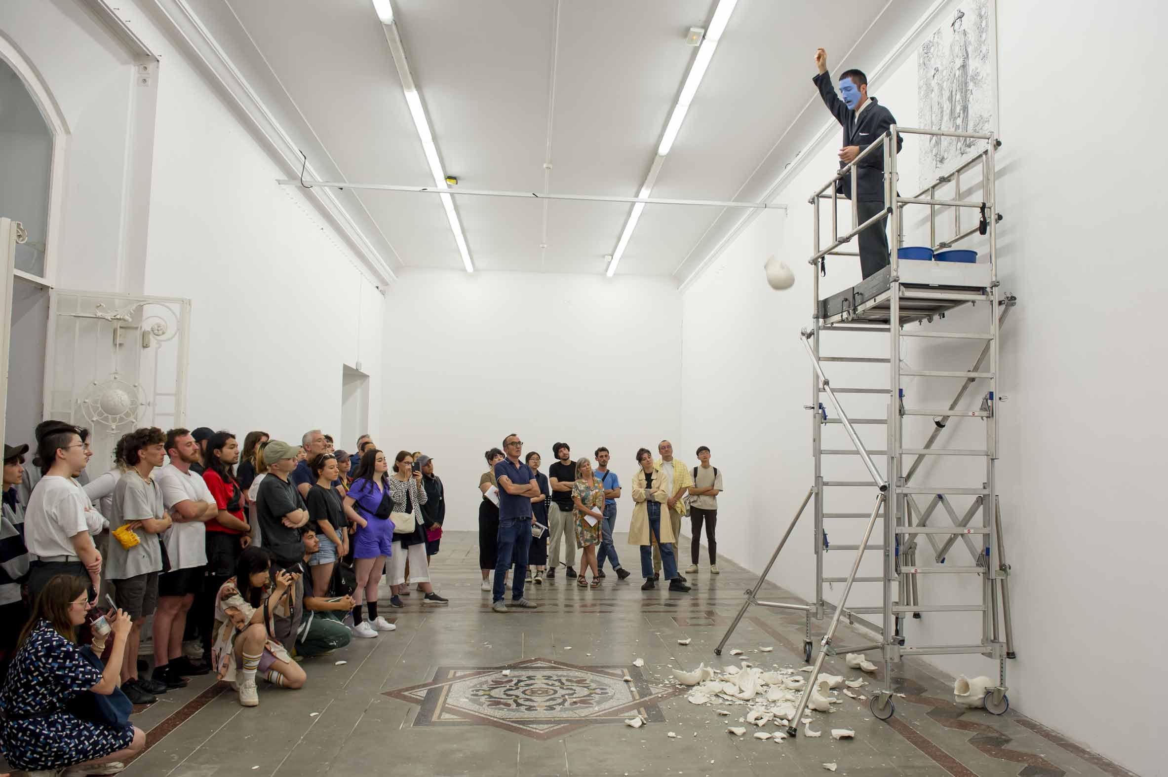 Performance mit Publikum, Performer steht auf einem Gerüst im Ausstellungsraum