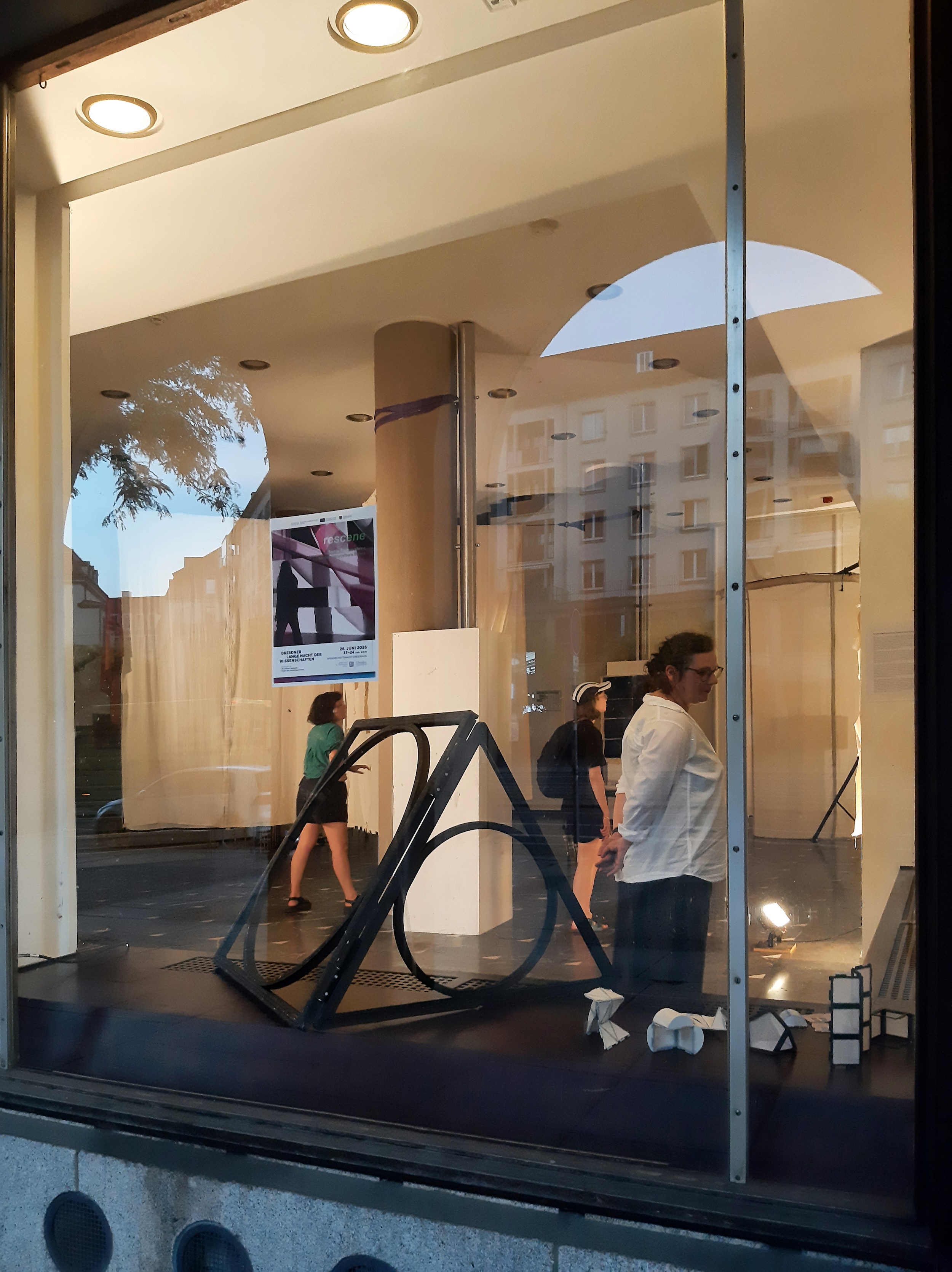 Ausstellung mit Besucher:innen, durch die Fenster des Raums fotografiert