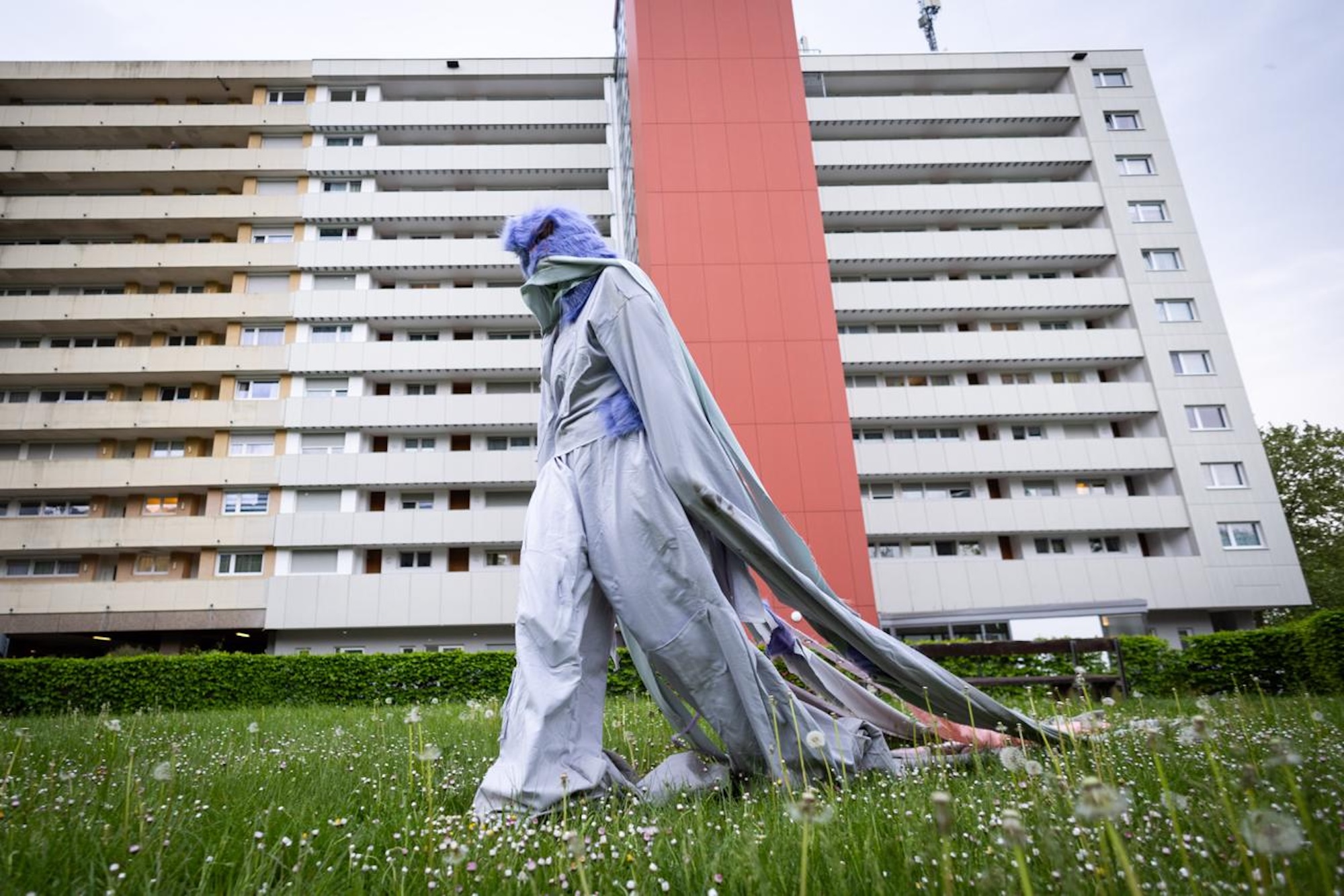 [Translate to Englisch:] Person in langem Gewand vor einem Hochhaus
