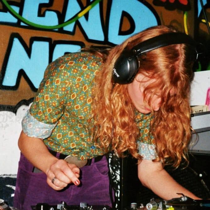 DJ Sylpid bei der Arbeit, wie sie sich über die Decks beugt
